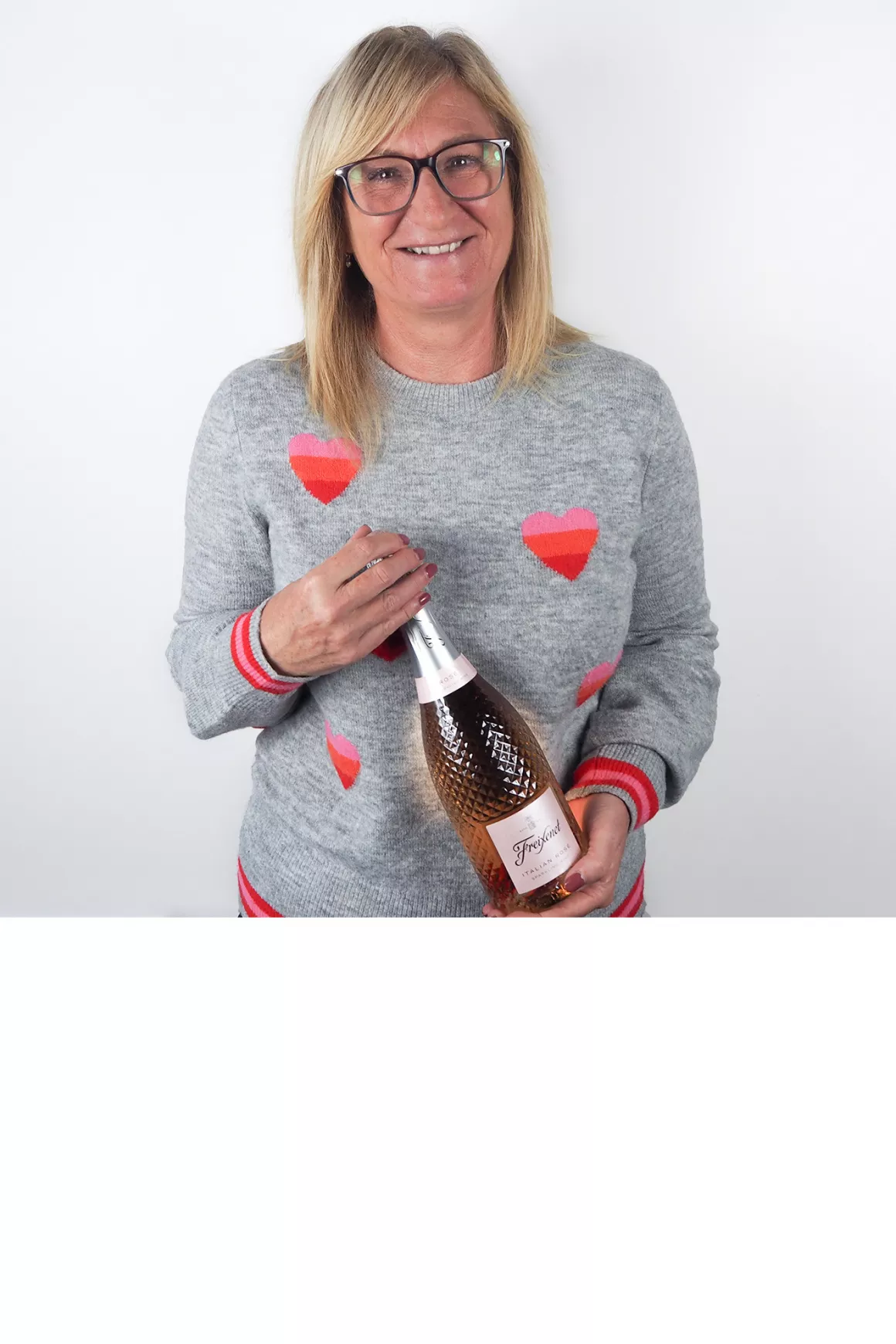 Karen Yaxley (accounts) with grey jumper with love hearts, holding bottle of Rose Prosecco