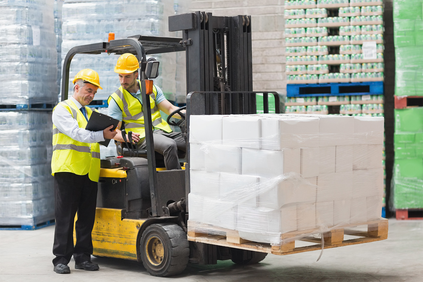 Forklift Driver talking to other warehouse worker while carrying delivery on forklift forks